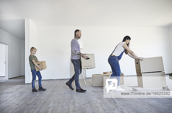 Familie hält Kartons auf Skateboard im neuen Haus