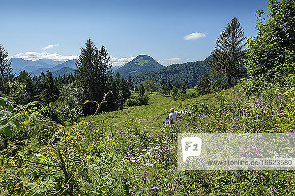 Senior woman relaxing in alpine meadow during summer