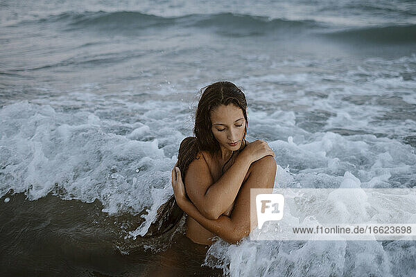 Frau mit verschränkten Armen beim Baden im Wasser am Strand