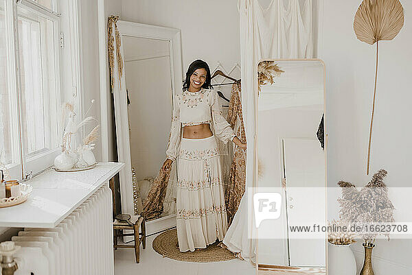 Smiling bride standing against mirror at home