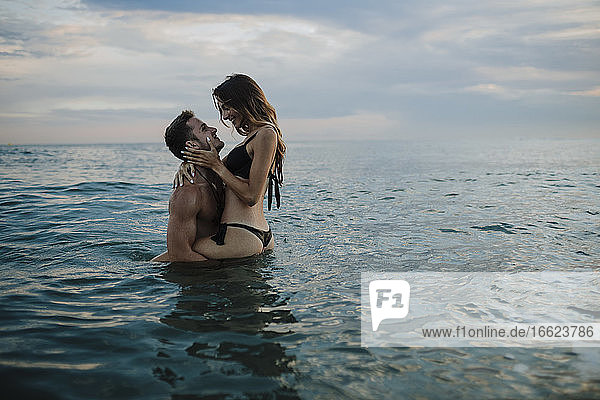 Junges Paar macht Romantik im Wasser am Strand bei Sonnenuntergang