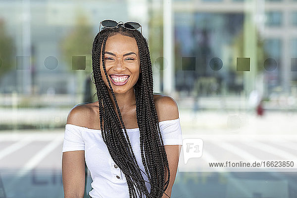 Smiling woman standing against glass wall in city