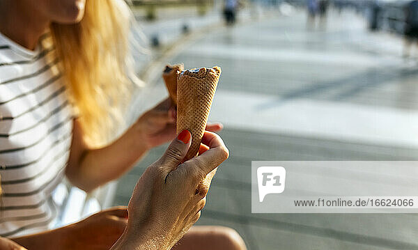 Junge Frauen essen Eis  während sie an einem sonnigen Tag ihre Freizeit in der Stadt verbringen