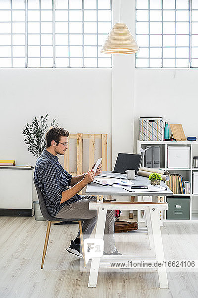 Architekt  der im Büro sitzend an einem digitalen Tablet arbeitet
