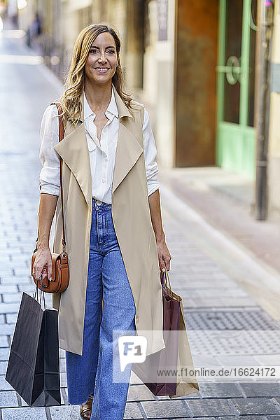Frau trägt Einkaufstasche beim Gehen auf dem Fußweg in der Stadt
