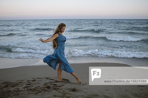 Schöne Frau tanzt im Stehen am Strand