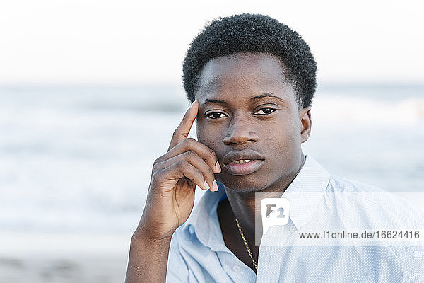 Nachdenklicher junger Mann am Strand sitzend