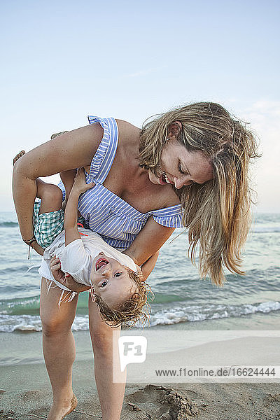 Mutter spielt mit Sohn am Strand stehend