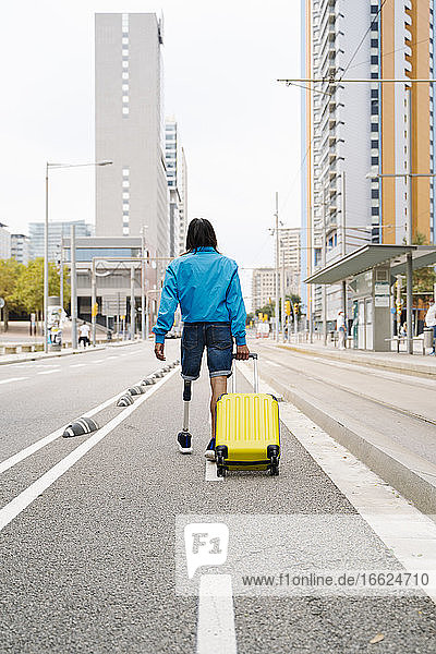 Junger Mann geht mit Gepäck auf der Straße in der Stadt