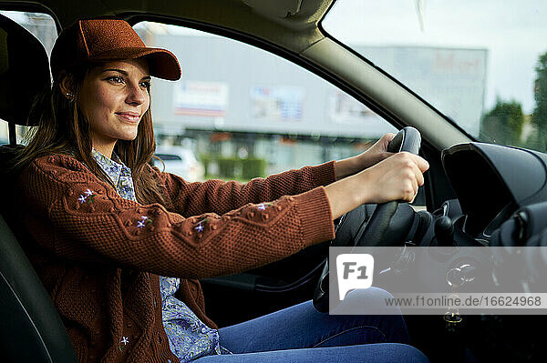 Young woman smiling while driving car in city