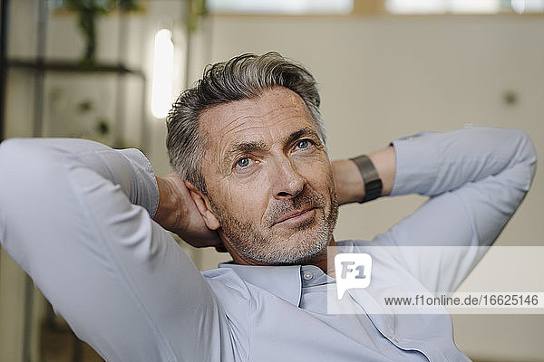 Businessman with hands behind head relaxing while sitting at office