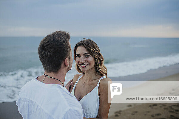 Lächelnde Frau steht mit Mann am Strand