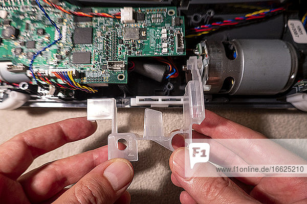 Hands of mature man repairing robotic vacuum cleaner