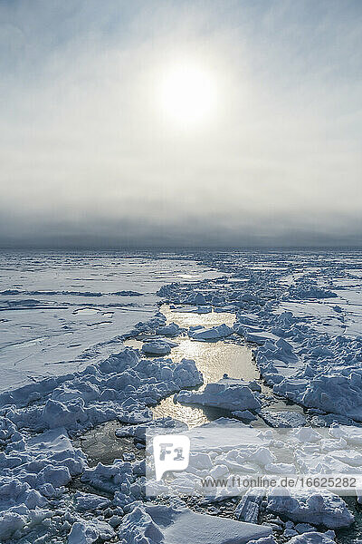 Sun shining over broken ice floating in Arctic Ocean