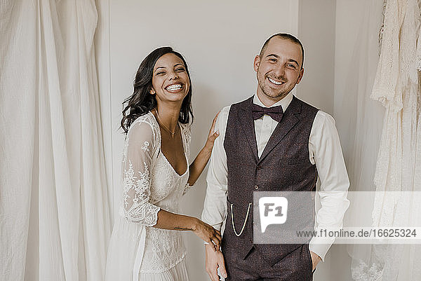 Bride and bridegroom smiling while standing at home