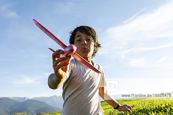 Junge spielt mit Flugzeug Spielzeug  während gegen klaren Himmel stehen