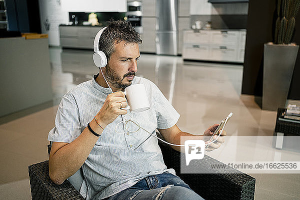 Businessman listening music through headphones while using smart phone at office