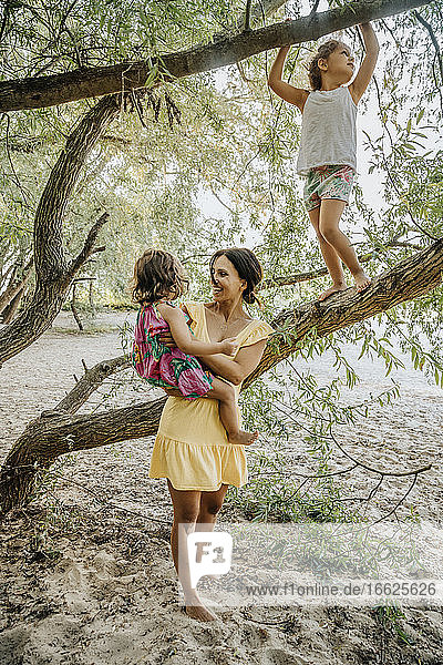 Mutter und Töchter stehen in der Nähe des Weidenbaums