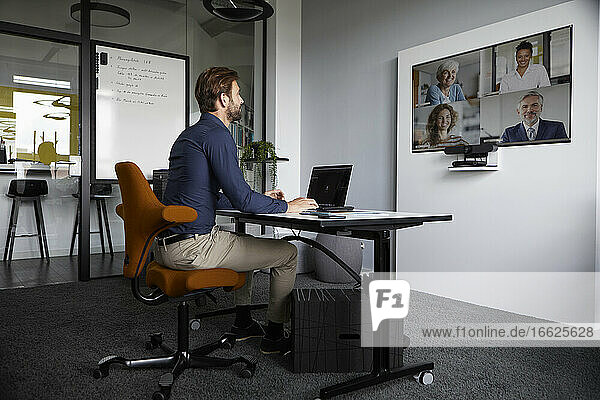 Geschäftsmann nimmt an einer Webkonferenz teil  während er im Büro sitzt