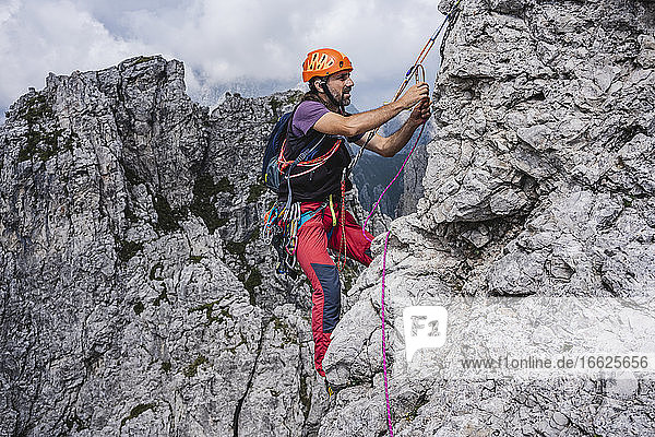 Männlicher Bergsteiger mit Seil beim Klettern am Berg  Europäische Alpen  Lecco  Italien
