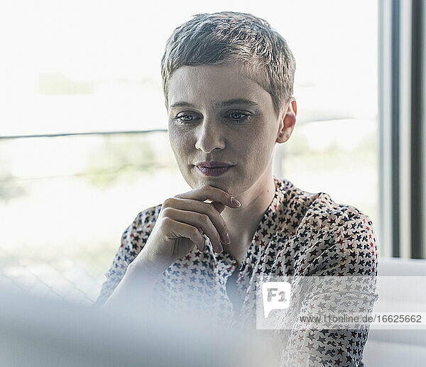 Close-up of thoughtful businesswoman with short hair sitting in office