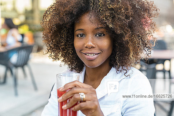 Mid adult woman drinking juice sitting at sidewalk cafe