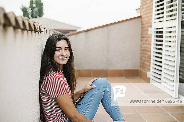 Lächelnde junge Frau auf dem Balkon