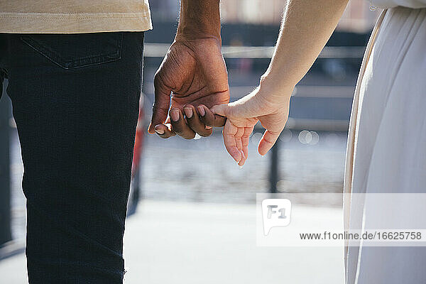 Paar hält Finger  während es auf einem Fußweg in der Stadt steht