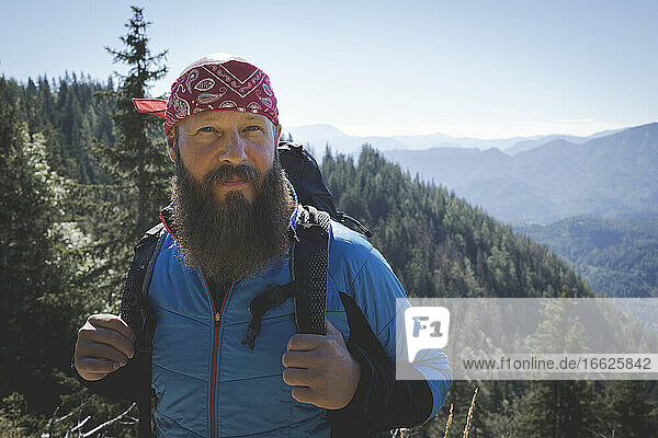 Bearded male hiker with backpack standing against mountains during sunny day  Otscher  Austria