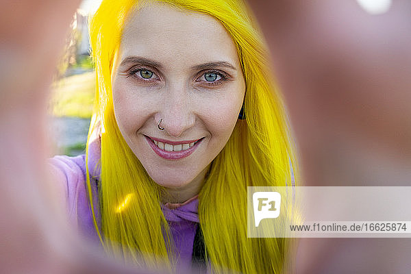 Hipster-Frau lächelt  während sie an einem sonnigen Tag im Freien steht