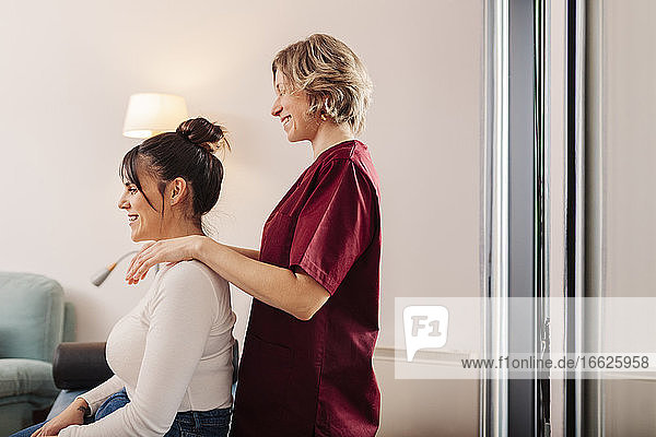 Smiling woman and physiotherapist applying physical therapy