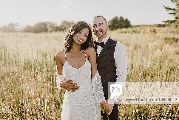 Smiling couple standing against agricultural field on sunny day
