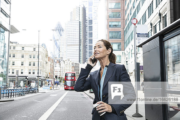 Reife Geschäftsfrau  die in der Stadt mit einem Mobiltelefon spricht