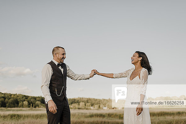 Heterosexual Couple holding hands while standing in agricultural field