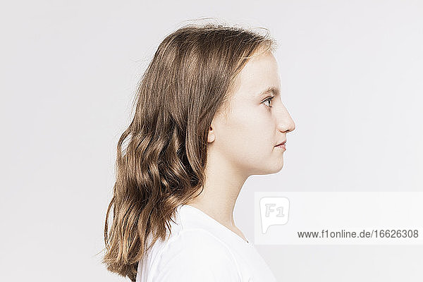 Close-up of thoughtful girl looking away against white background