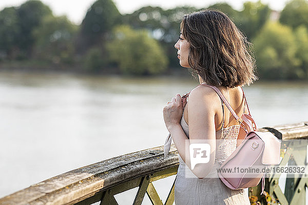 Junge Frau schaut auf den Fluss  während sie auf einem Steg steht