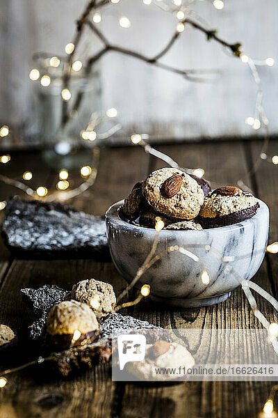 Weihnachtsbeleuchtung und Schale mit Lebkuchen und Mandeln