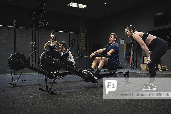 Athletes exercising with rowing machine at gym