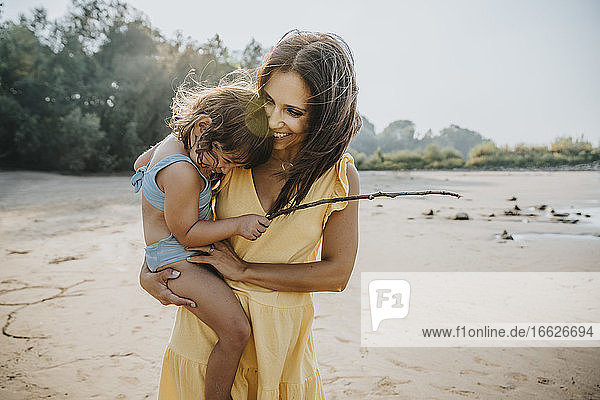 Glückliche Mutter hält ihre Tochter am Strand in den Armen