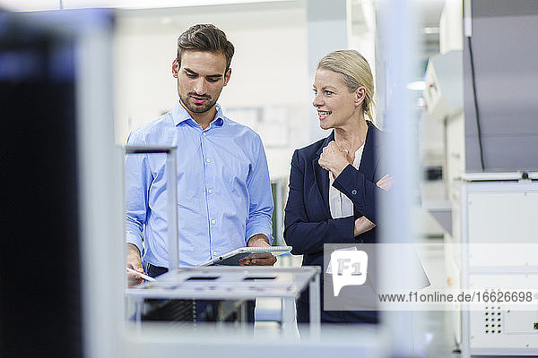 Businesswoman discussing with young male technician in illuminated factory