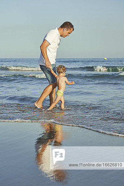 Father and son playing together in water at beach