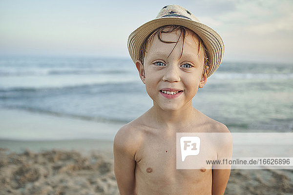 Boy smiling while standing against sea at beach