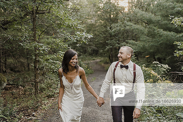 Couple holding hands while walking in forest