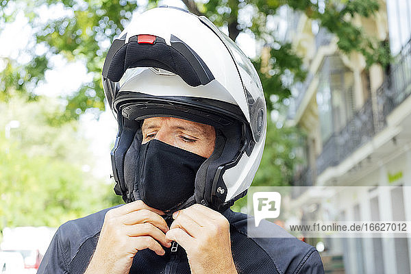 Male biker putting on helmet