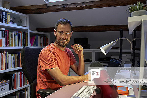 Lächelnder Mann  der zu Hause sitzend am Laptop arbeitet