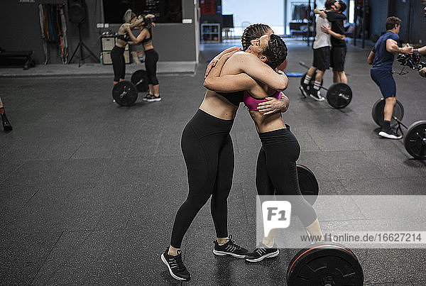 Athletes hugging each other while standing at gym