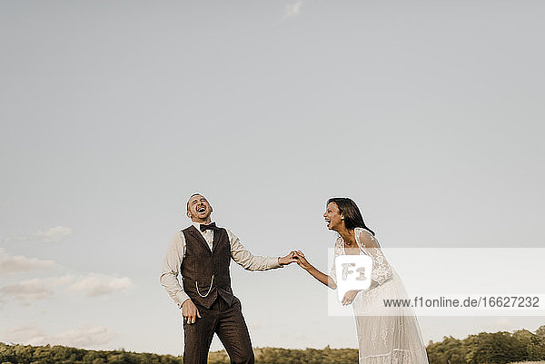 Fröhliches Paar  das lachend auf einem landwirtschaftlichen Feld steht