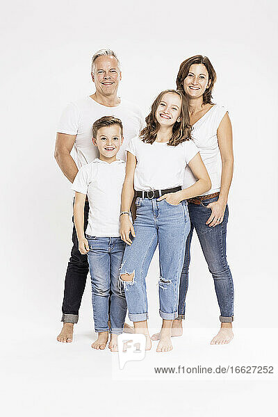 Glückliche Familie posiert im Stehen vor weißem Hintergrund