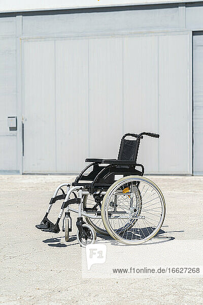 Empty wheelchair at military base on sunny day