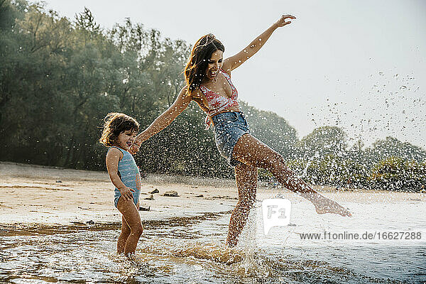 Mother and daughter enjoying in water at beach